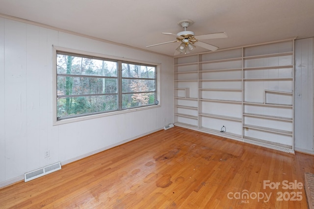 unfurnished room featuring wood-type flooring, a wealth of natural light, and ceiling fan