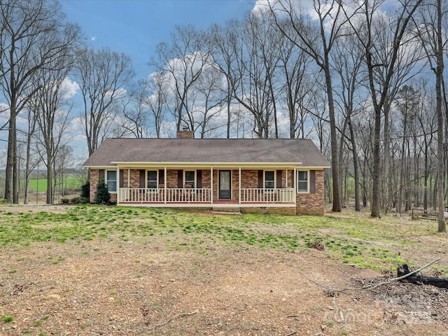 view of front of house featuring crawl space, brick siding, covered porch, and a chimney