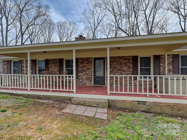 exterior space featuring a porch, brick siding, and a chimney