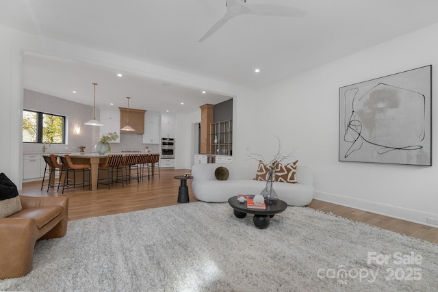 living room with ceiling fan and light wood-type flooring