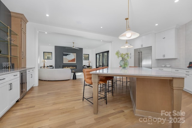 kitchen featuring built in refrigerator, a center island, a breakfast bar area, and white cabinets