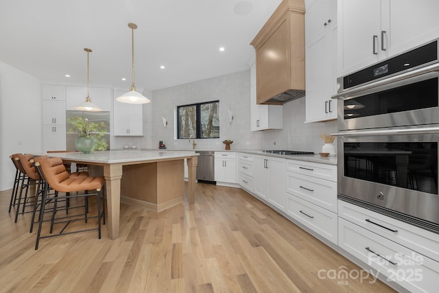 kitchen with appliances with stainless steel finishes, decorative light fixtures, white cabinets, backsplash, and a center island