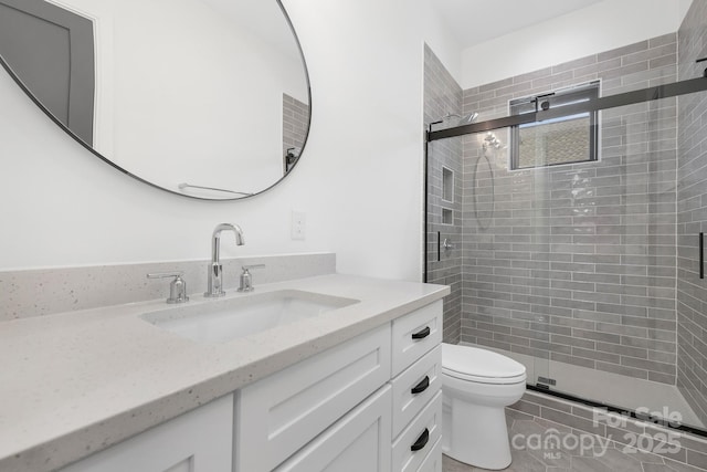 bathroom featuring vanity, tile patterned flooring, a shower with door, and toilet