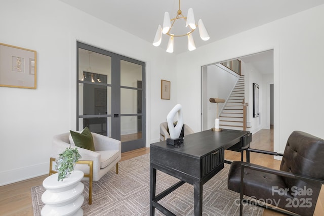 home office with hardwood / wood-style flooring, an inviting chandelier, and french doors