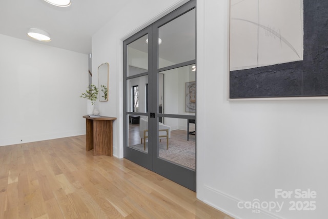 corridor featuring light hardwood / wood-style floors and french doors