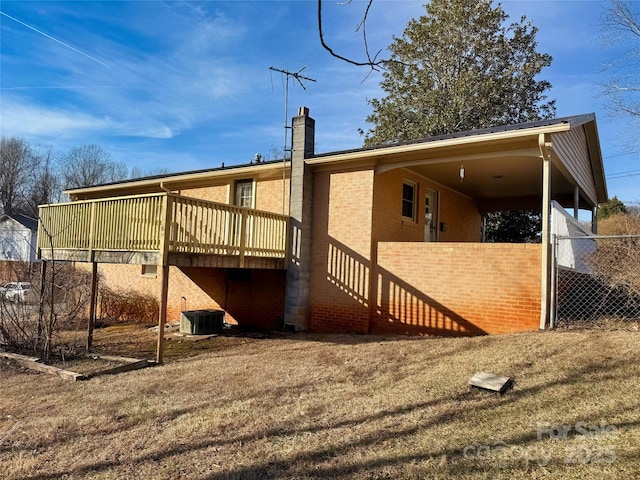 rear view of house featuring a deck and a lawn