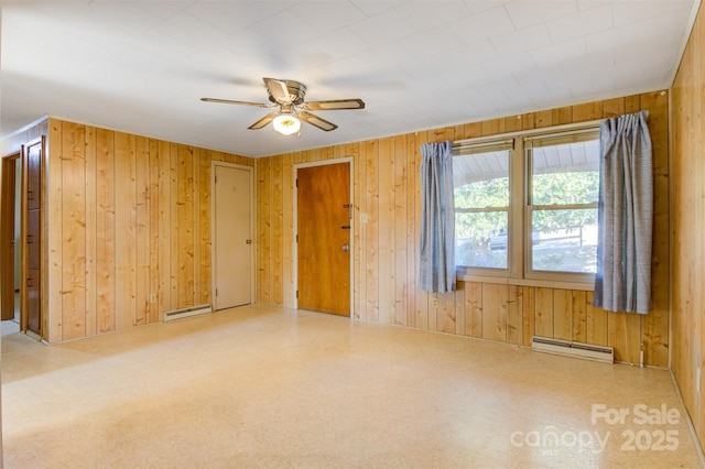 unfurnished room featuring a baseboard heating unit, wooden walls, and ceiling fan