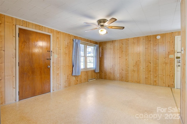 empty room with a baseboard radiator, wooden walls, and ceiling fan