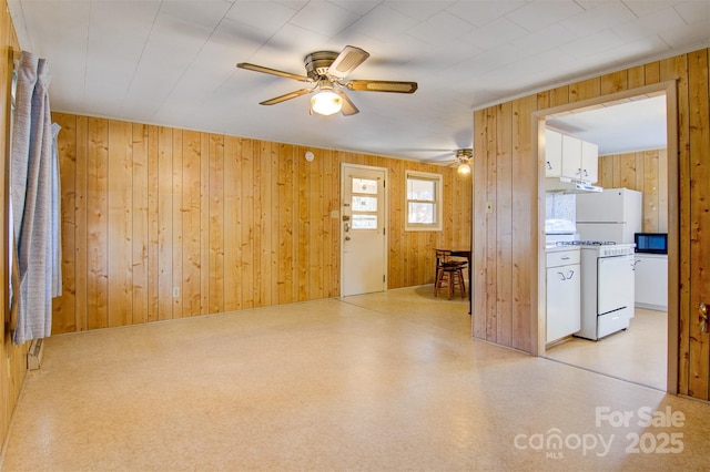 interior space featuring ceiling fan and wood walls