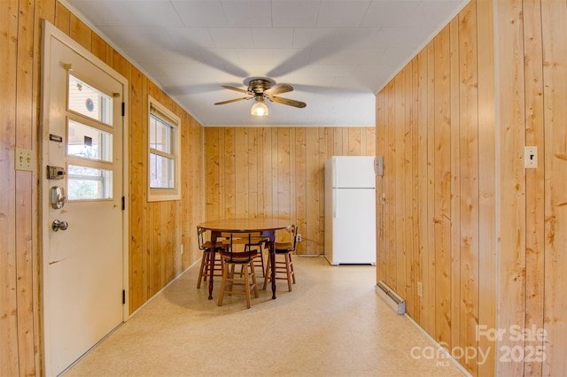 dining area with ceiling fan and wood walls