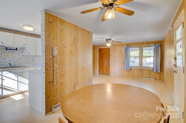 dining room with sink, baseboard heating, and wood walls