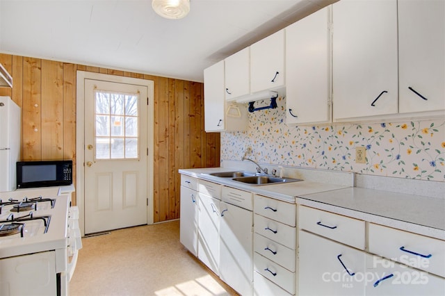 kitchen featuring sink, white cabinets, wooden walls, and white range with gas cooktop