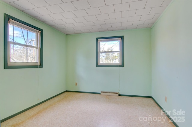 unfurnished room with a baseboard heating unit and plenty of natural light