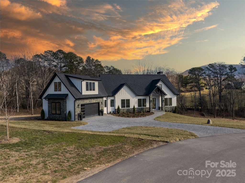 view of front of property with a garage, a mountain view, and a lawn