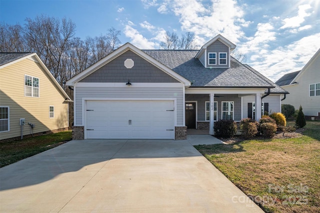 view of front of property featuring a garage, covered porch, and a front lawn