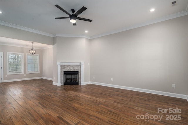 unfurnished living room featuring a tiled fireplace, crown molding, dark wood-type flooring, and ceiling fan with notable chandelier