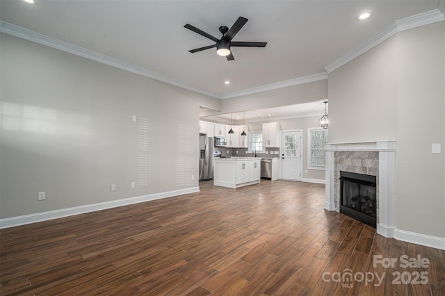 unfurnished living room featuring dark wood-type flooring, sink, crown molding, a tile fireplace, and ceiling fan