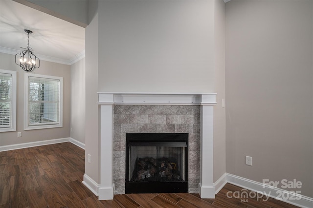 room details featuring a tile fireplace, ornamental molding, hardwood / wood-style floors, and a notable chandelier