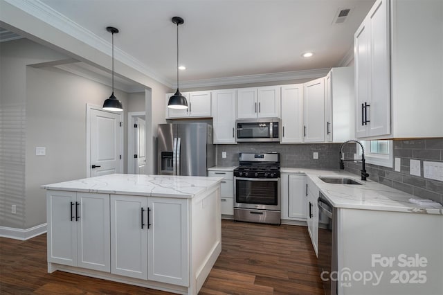 kitchen with sink, appliances with stainless steel finishes, white cabinetry, hanging light fixtures, and a center island