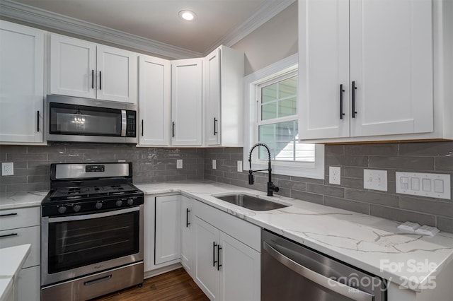 kitchen with appliances with stainless steel finishes, sink, white cabinets, and backsplash