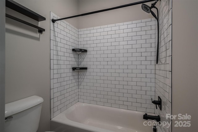 bathroom featuring tiled shower / bath combo and toilet