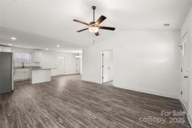 unfurnished living room featuring lofted ceiling, sink, ceiling fan with notable chandelier, and dark hardwood / wood-style flooring