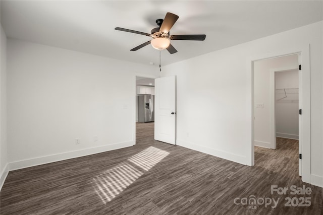 unfurnished bedroom featuring dark wood-type flooring, a spacious closet, stainless steel fridge with ice dispenser, a closet, and ceiling fan