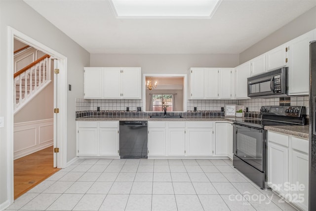 kitchen featuring tasteful backsplash, sink, white cabinets, light tile patterned floors, and black appliances