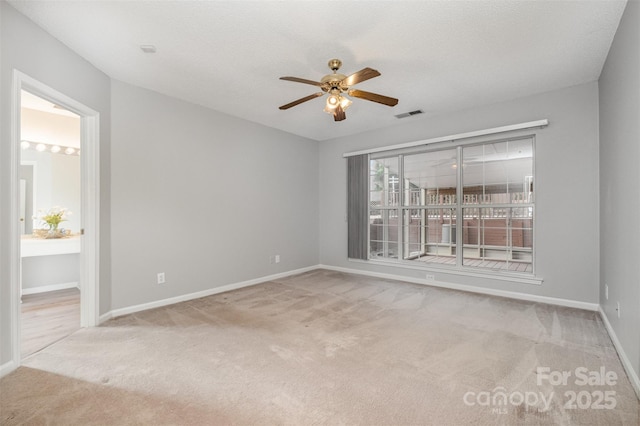 spare room with a textured ceiling, light colored carpet, and ceiling fan