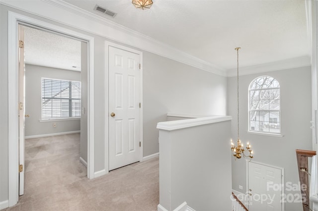 hallway with an inviting chandelier, light colored carpet, crown molding, and a textured ceiling