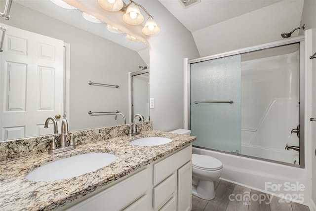 full bathroom with lofted ceiling, shower / bath combination with glass door, hardwood / wood-style floors, vanity, and toilet