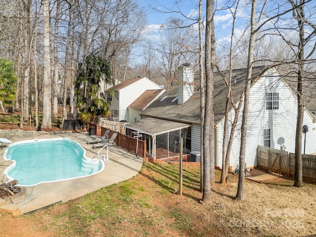 view of swimming pool with a patio, a diving board, a lawn, a sunroom, and central AC