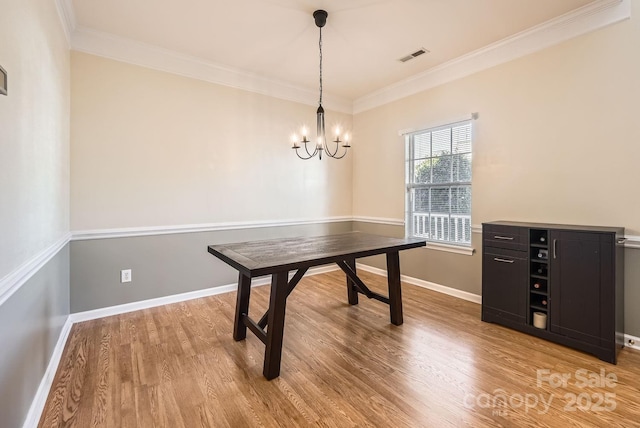 office space featuring ornamental molding, an inviting chandelier, and light hardwood / wood-style floors