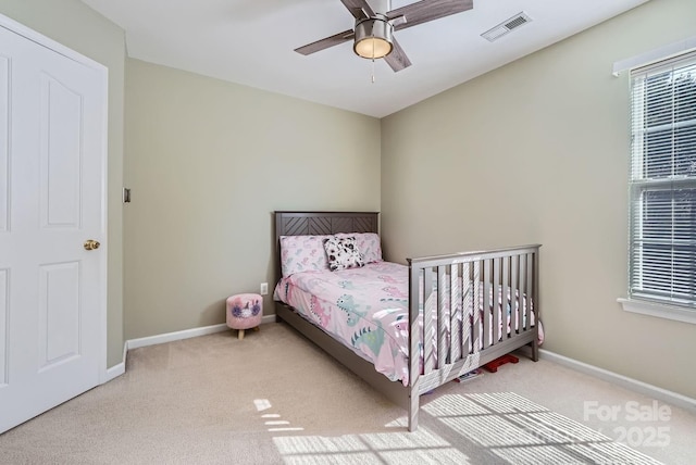 bedroom with ceiling fan, light colored carpet, and multiple windows