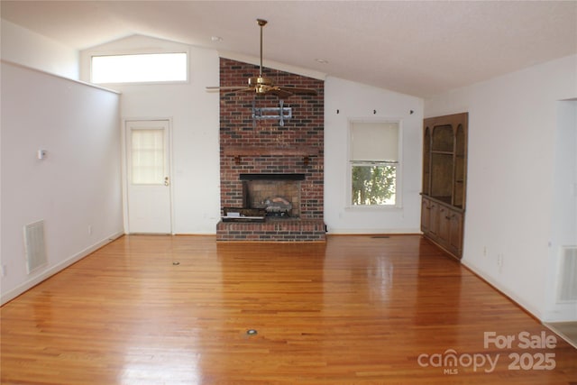 unfurnished living room featuring lofted ceiling, a brick fireplace, hardwood / wood-style floors, and ceiling fan