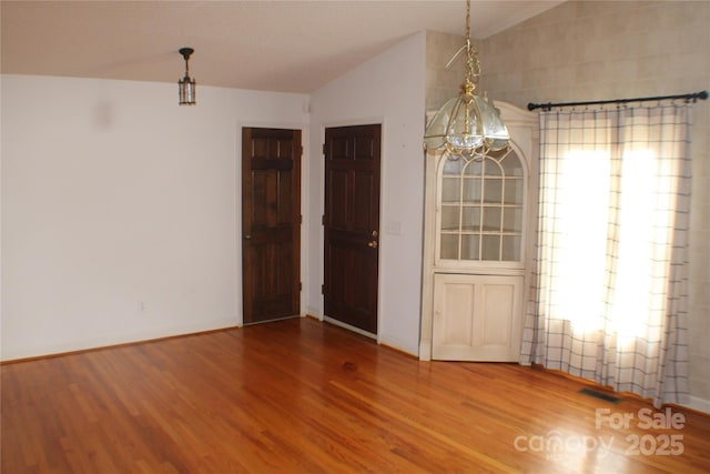 unfurnished dining area with lofted ceiling and hardwood / wood-style floors