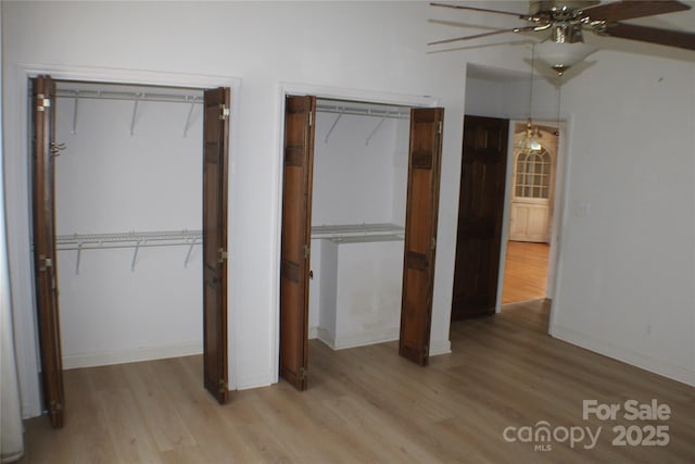 unfurnished bedroom with multiple closets, ceiling fan, and light hardwood / wood-style floors