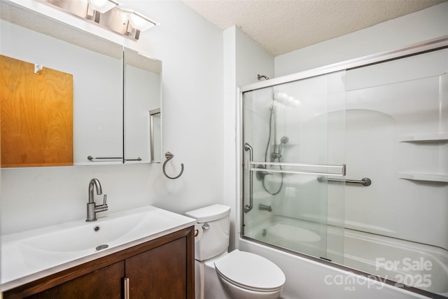 full bathroom featuring vanity, combined bath / shower with glass door, toilet, and a textured ceiling