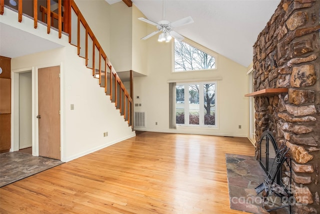 unfurnished living room with high vaulted ceiling, a fireplace, light hardwood / wood-style floors, and ceiling fan