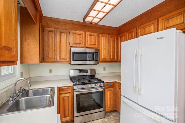 kitchen with appliances with stainless steel finishes, sink, and a textured ceiling