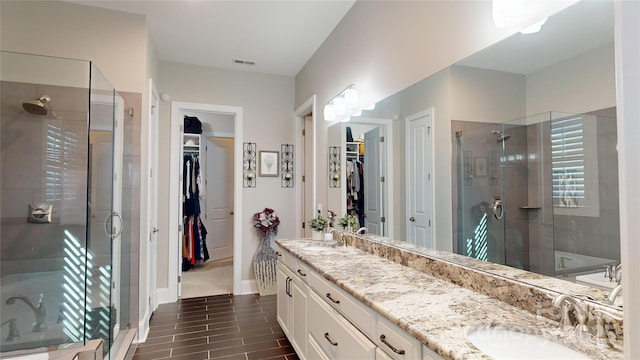 full bath with double vanity, visible vents, a shower stall, and a sink