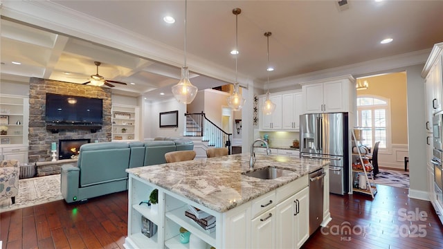 kitchen featuring sink, white cabinetry, a center island with sink, appliances with stainless steel finishes, and beam ceiling