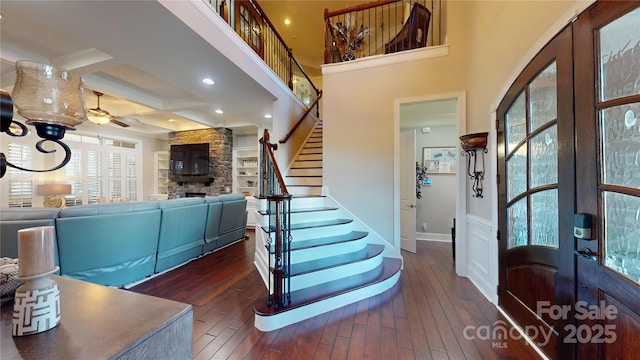 foyer entrance featuring a ceiling fan, coffered ceiling, a fireplace, french doors, and wood-type flooring