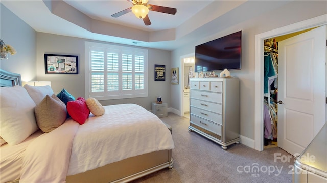 bedroom featuring a raised ceiling, a ceiling fan, a closet, baseboards, and light colored carpet