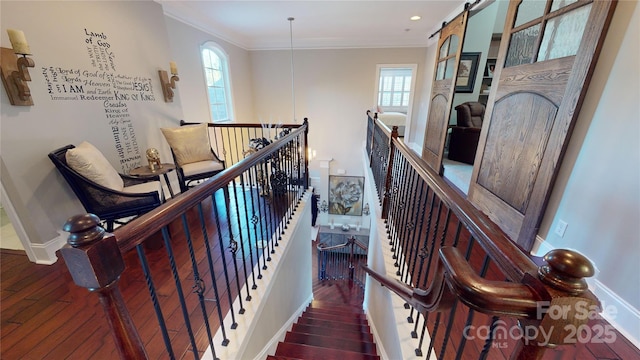 staircase featuring hardwood / wood-style flooring, ornamental molding, and a barn door