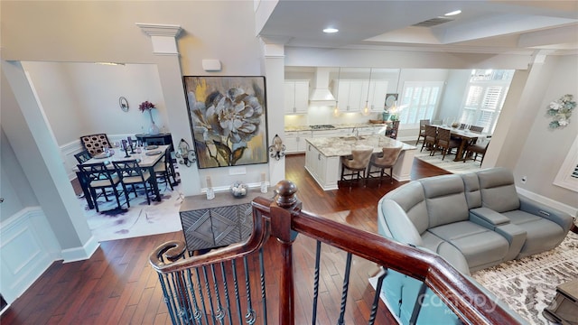 living room with crown molding, dark hardwood / wood-style flooring, sink, and ornate columns