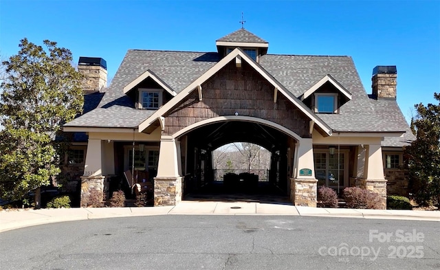 craftsman-style house with stucco siding, stone siding, roof with shingles, and a chimney