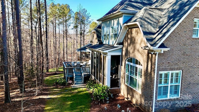 exterior space featuring a yard, a deck, and a sunroom