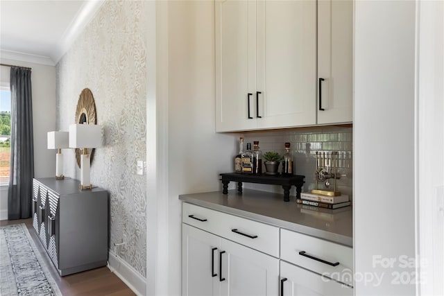 bar with crown molding, white cabinets, light wood-type flooring, and decorative backsplash