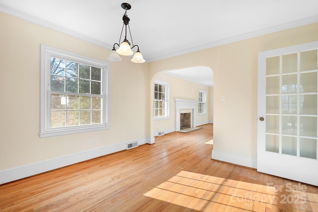 unfurnished dining area featuring crown molding, an inviting chandelier, and light wood-type flooring